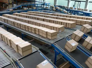 Mulitple rows of cardboard boxes on conveyor belts in a factory