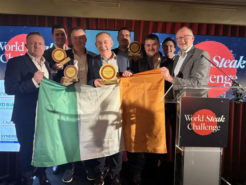 Three men accepting award, holding Irish flag