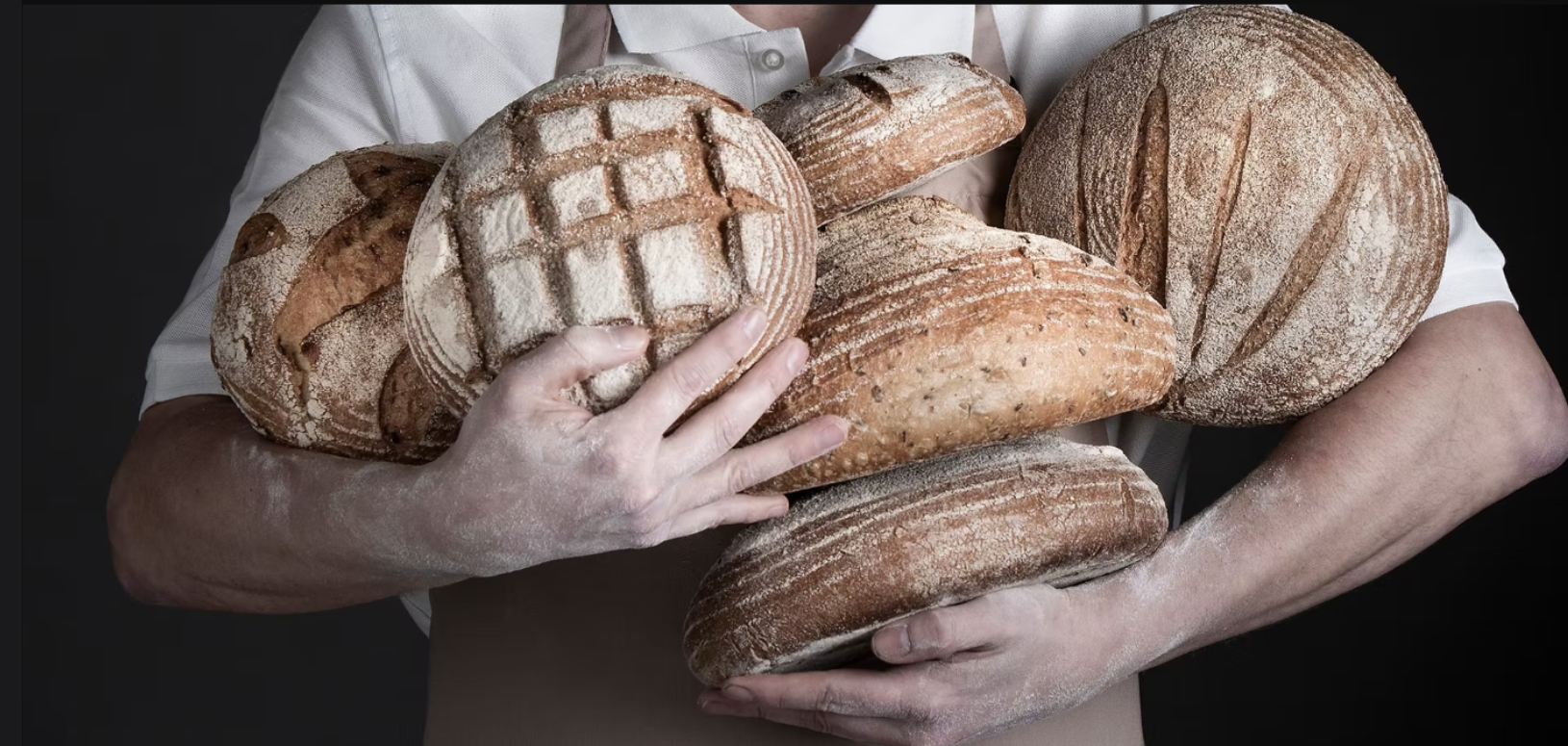 Man holding 6 loaves of freshly baked bread