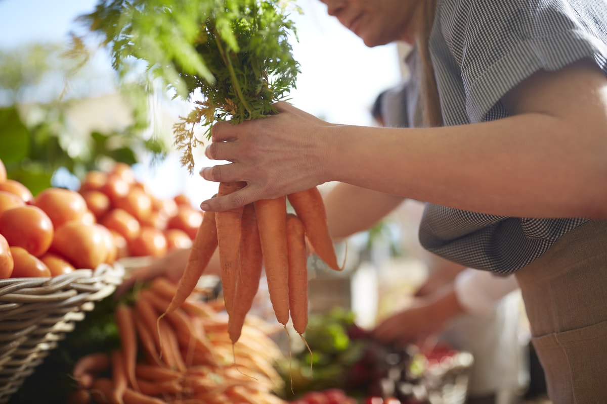 man picking out carrots at farmers market